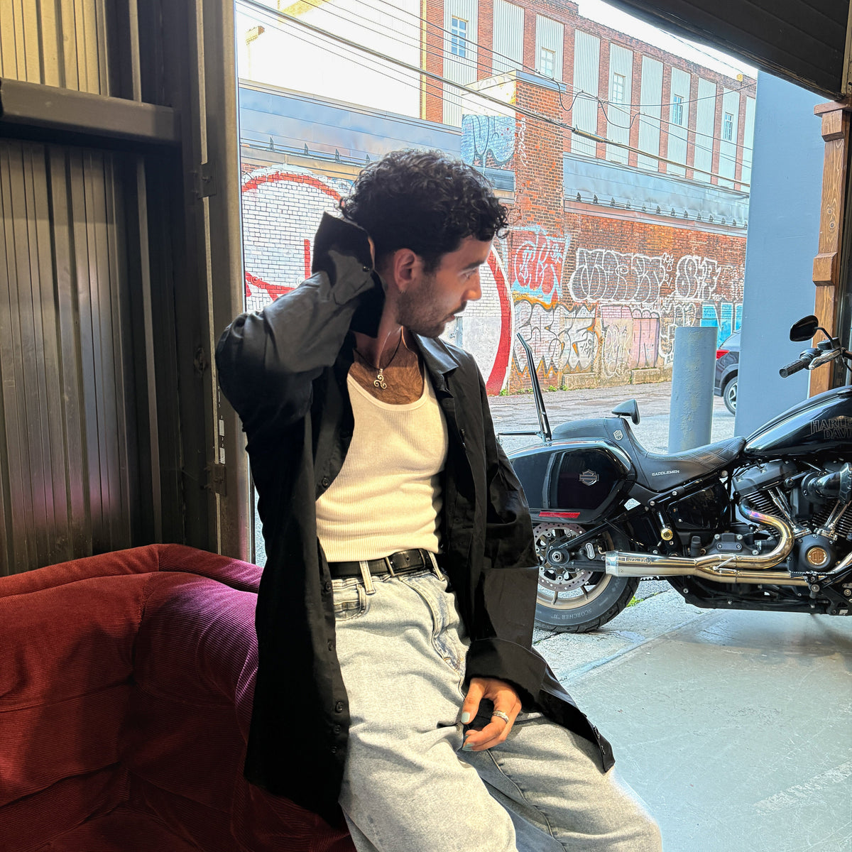 Model in CMPLX black button-down shirt layered look beside motorcycle, Complex Paradox streetwear