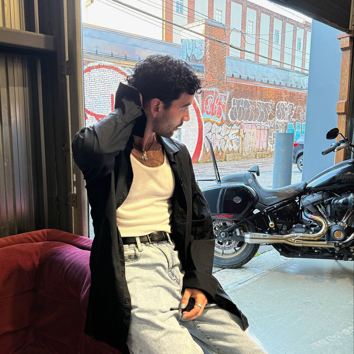 Model in CMPLX black button-down shirt layered look beside motorcycle, Complex Paradox streetwear