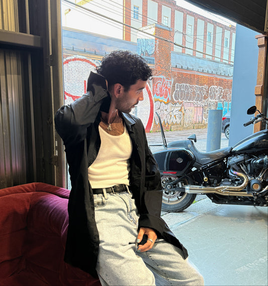 Model in CMPLX black button-down shirt layered look beside motorcycle, Complex Paradox streetwear