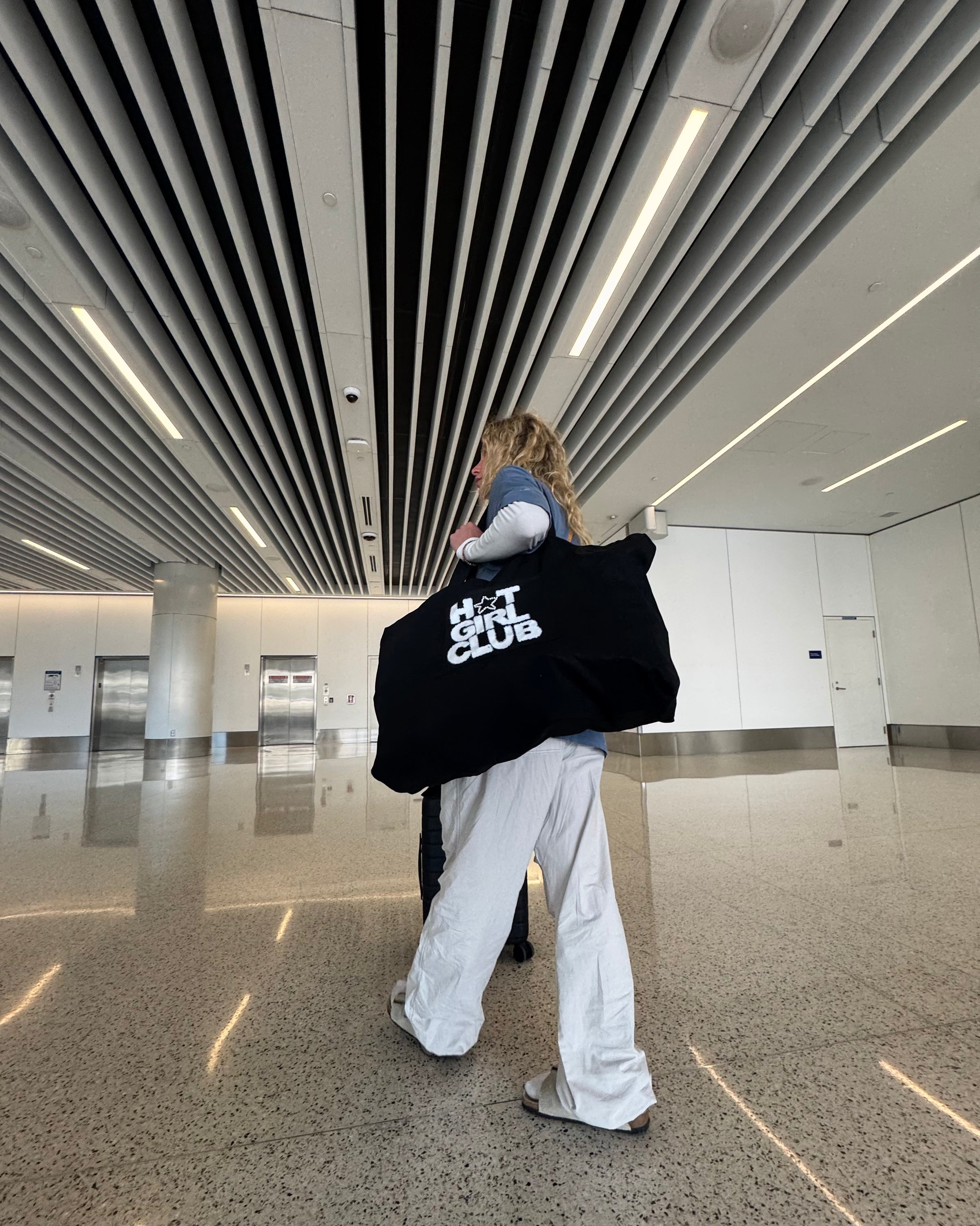 CMPLX Hot Girl Club duffel bag carried through airport terminal, Complex Paradox lookbook